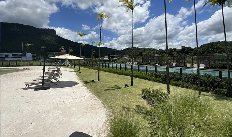 Área de lazer integrada à natureza com guarda-sóis e piscina do condomínio Reserva da Pedra em Palhoça/SC